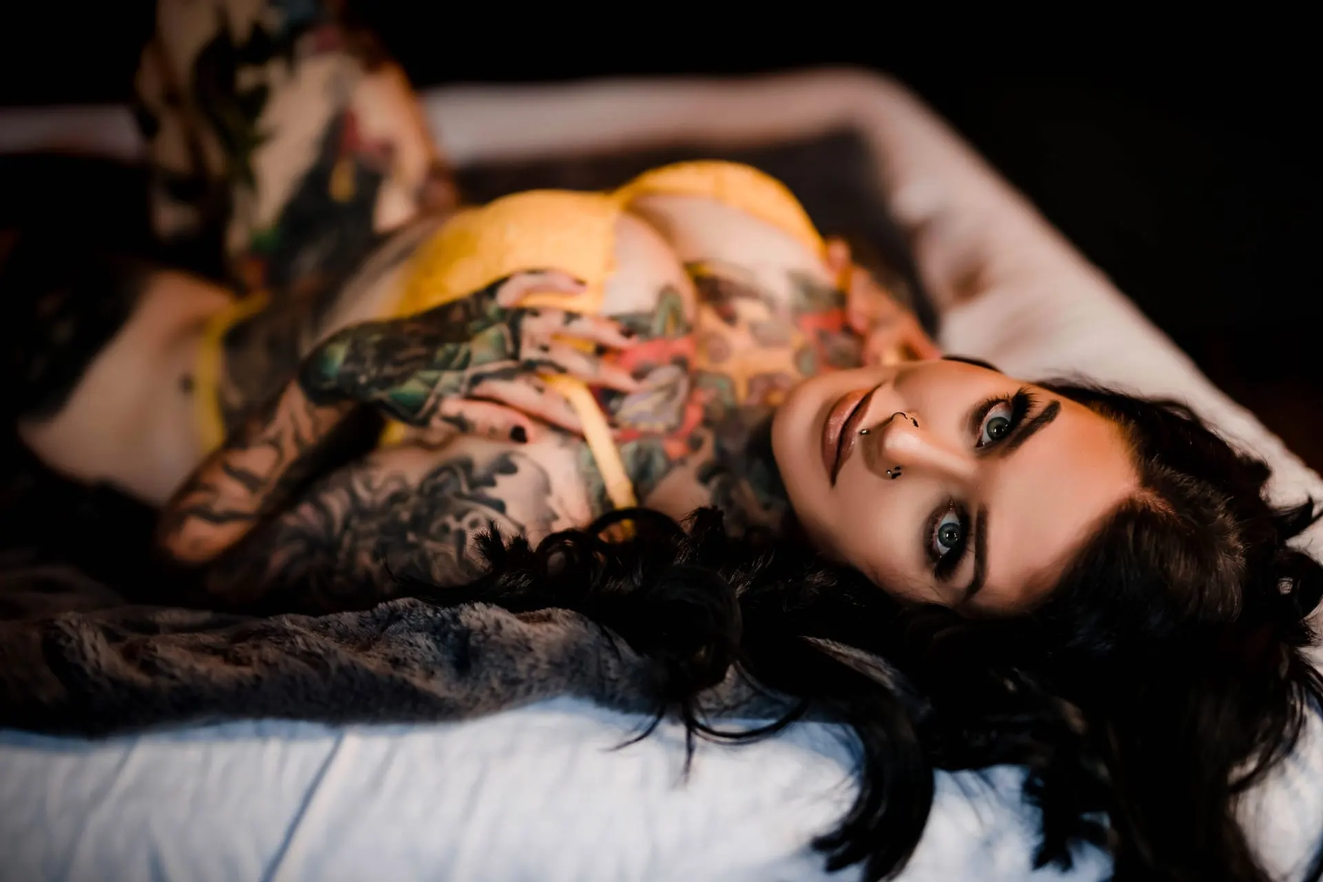 Woman in yellow lace lingerie lying back on a bed, gazing upward