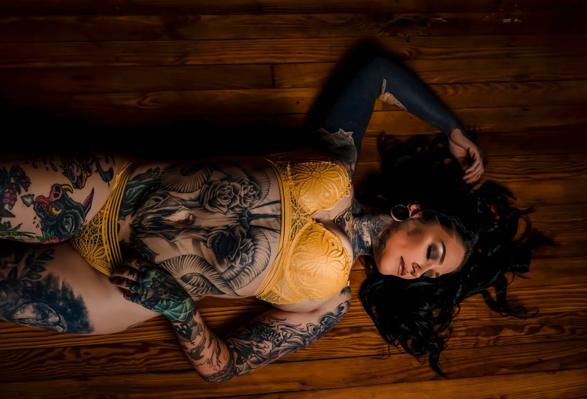 Overhead view of a woman in yellow lace lying on a wooden floor